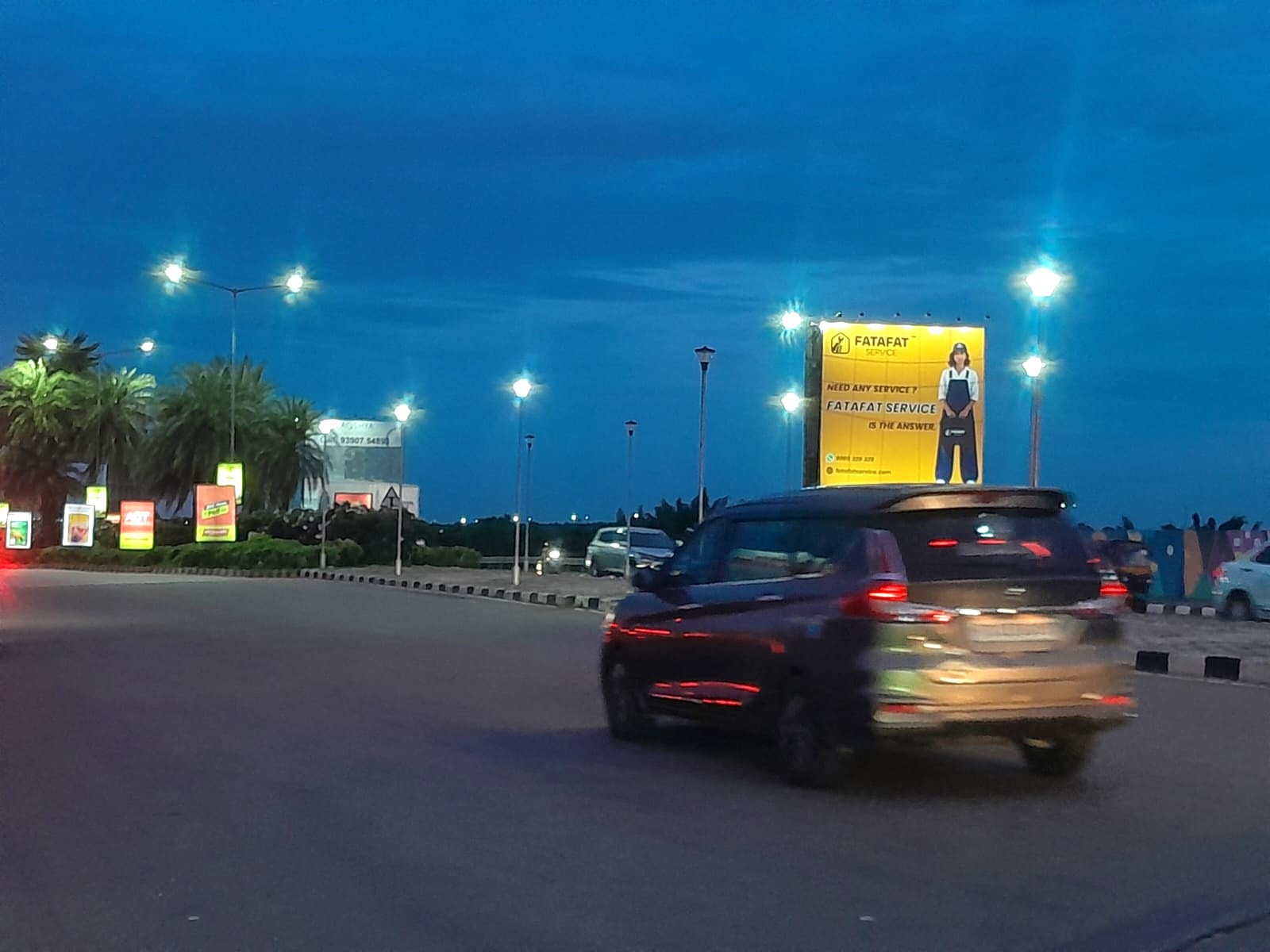 Lit FatafatService billboard beside the airport road in Hyderabad at dusk